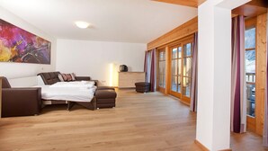 A spacious bedroom with a bed, a sofa, and a desk. There is a large window with curtains, a painting on the wall, and a wooden ceiling. - Chalet in Pinzgau near Ski Slopes (Wald im Pinzgau)