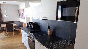 A modern kitchen with white cabinets, a black countertop, and stainless steel appliances. - Chalet in Pinzgau near Ski Slopes (Wald im Pinzgau)