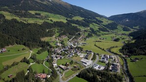 An aerial view of a small town with a winding road, surrounded by green fields and mountains. - Chalet in Pinzgau near Ski Slopes (Wald im Pinzgau)