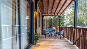 A wooden deck with a table and chairs, a small Christmas tree, and a glass enclosure on one side. - Club del Sole Val di Fiemme  (Bellamonte)