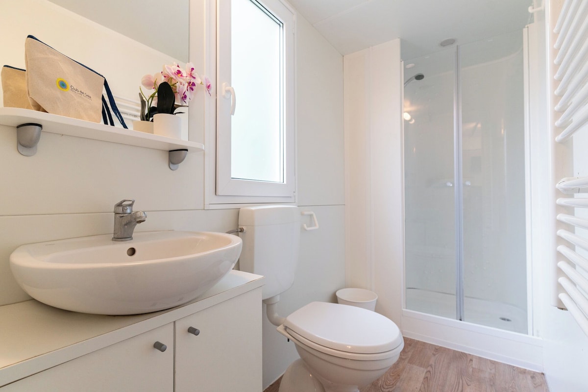 A bathroom with a white sink, toilet, and glass-enclosed shower.