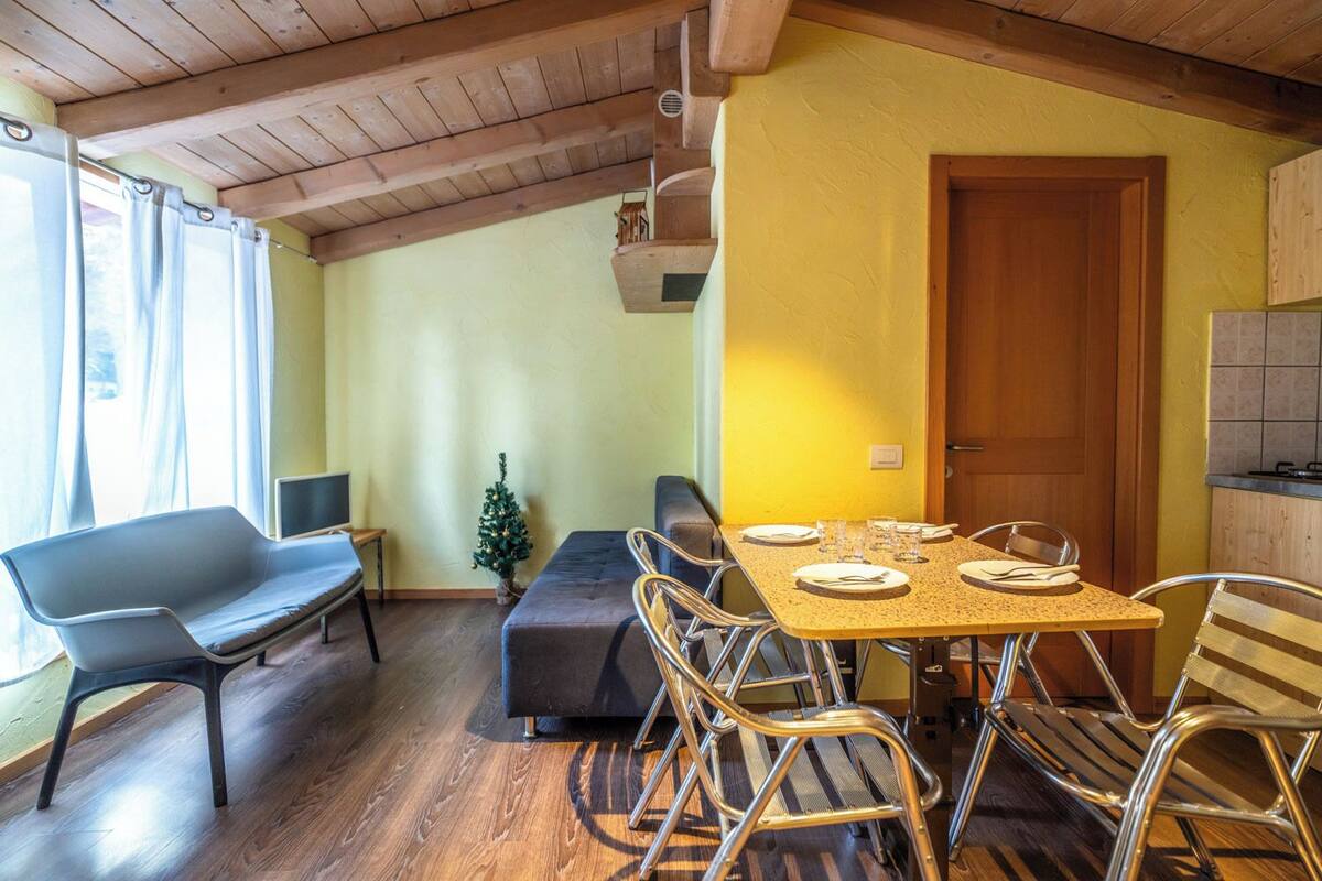 A dining area with a table set for four, a bench, and a small Christmas tree.