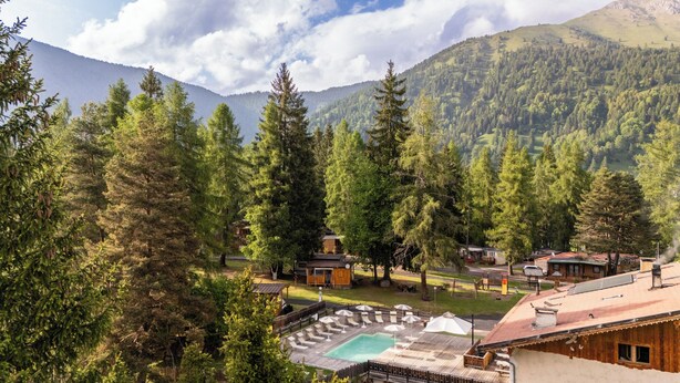 A resort with a pool, cabins, and a mountainous backdrop. - Club del Sole Val di Fiemme  (Bellamonte)