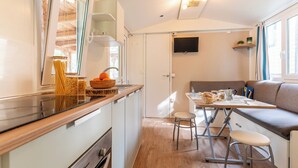 A compact kitchen with a countertop, a dining area with a table and chairs, and a sofa. - Club del Sole Val di Fiemme  (Bellamonte)