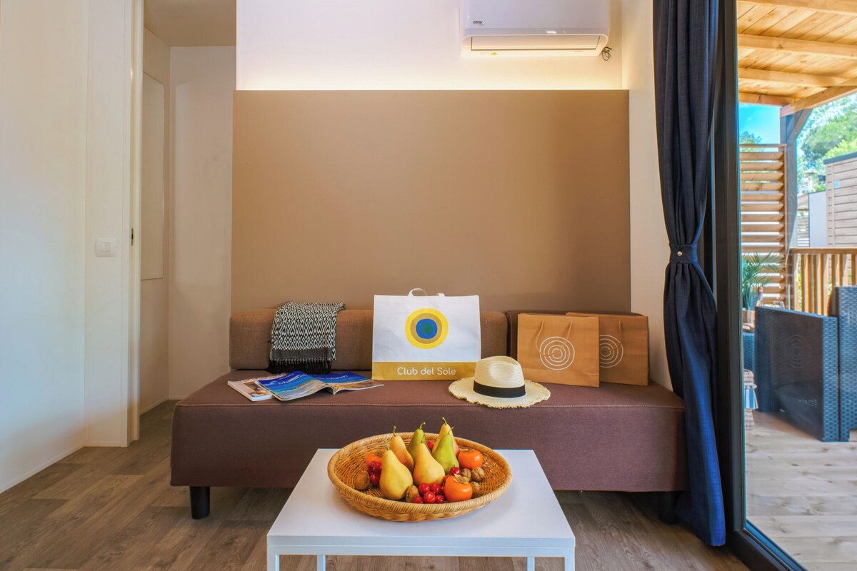 A cozy room with a sofa, a basket of fruit, and a white table.