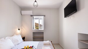 Ein Hotelzimmer mit einem Bett, einem Frühstücksbrett, einem Flachbildfernseher, einem Fenster und einer Wand-Klimaanlage.