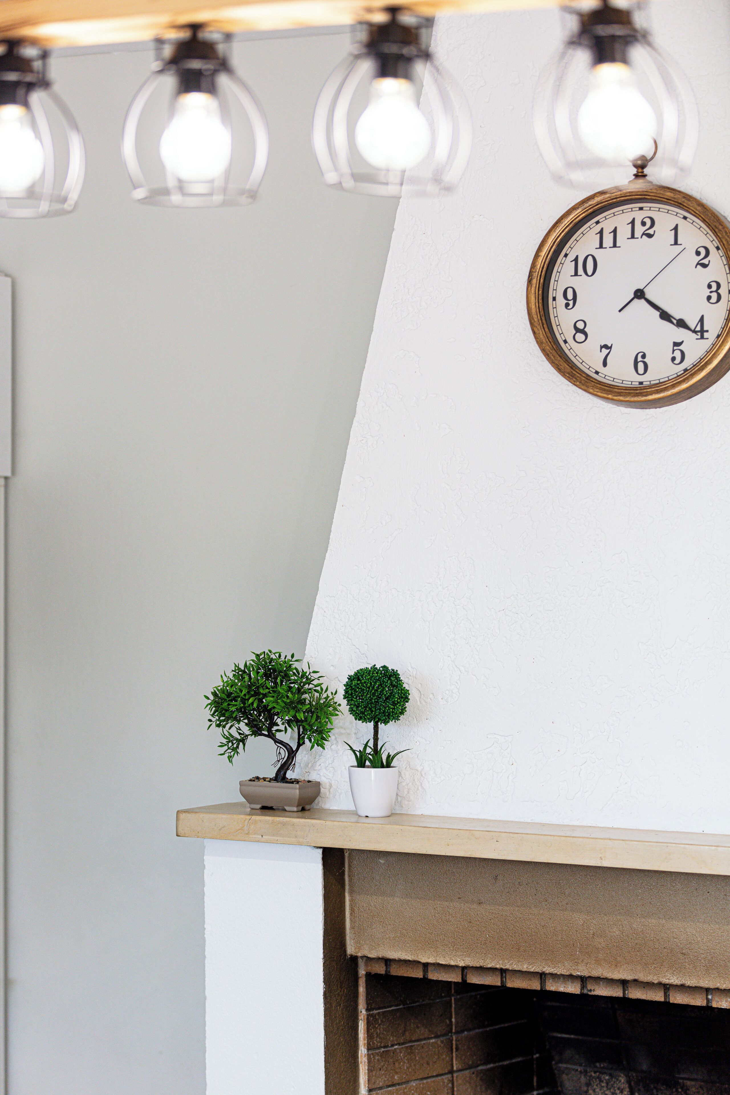 A wall-mounted clock, a small potted plant, and a shelf with a bonsai tree.