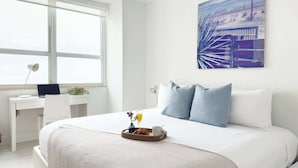 A modern hotel room with a large bed, a desk, and a window with a view of a bridge. - Serene Studio Suite with Bay Views - Coconut Grove (Miami)