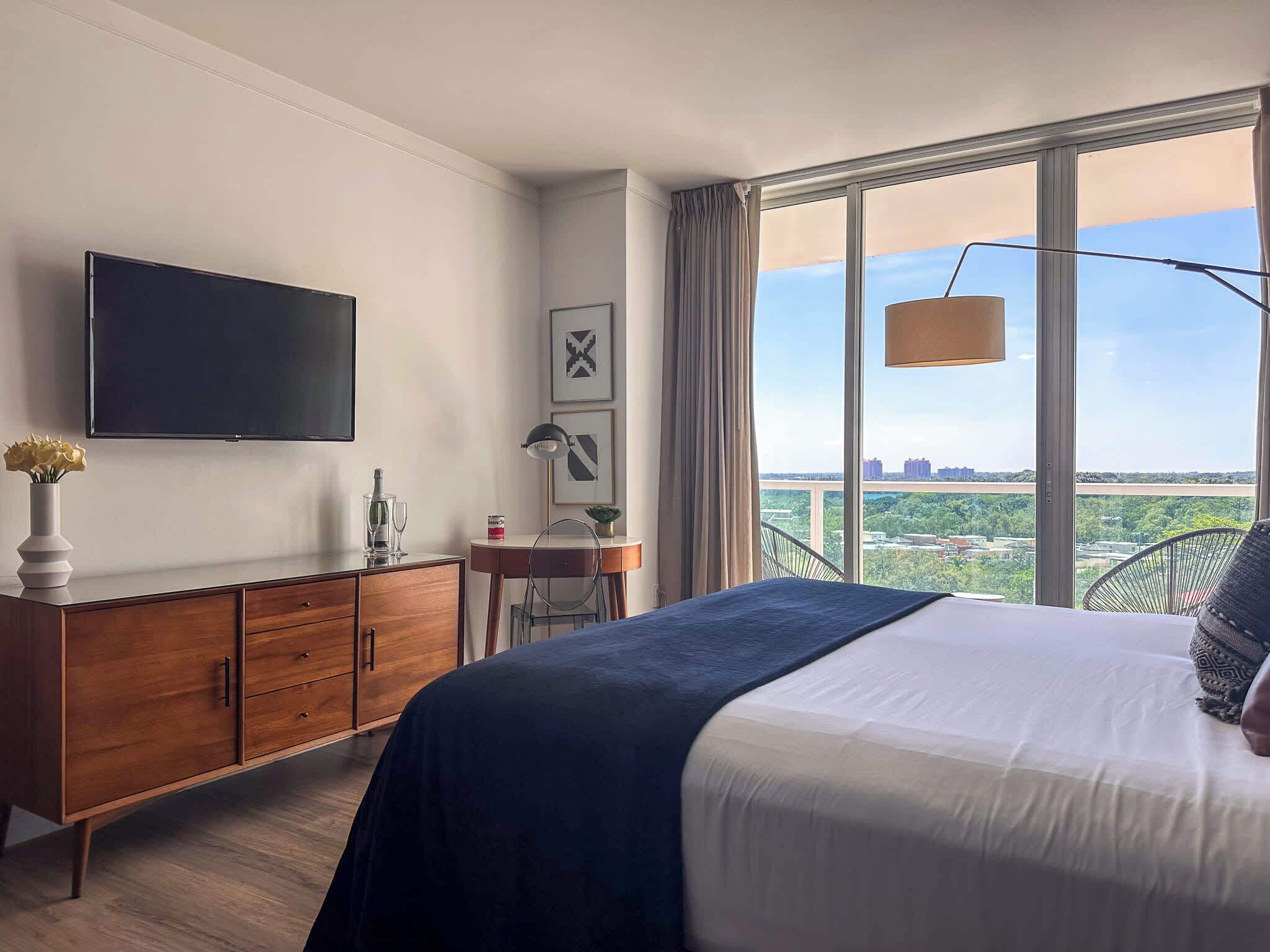 Une chambre d’hôtel avec un lit, une télévision, un bureau avec une lampe et une vue sur la ville.