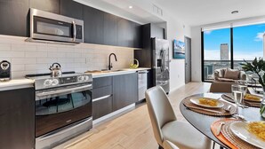 A modern kitchen with dark cabinetry, a stainless steel microwave, and a built-in oven.
