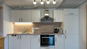A modern kitchen with white cabinets, a stainless steel oven, and a built-in range hood. - Alpine House in Prebl near Klippitztörl Ski Area (Prebl)