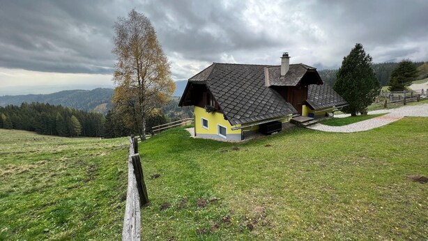 A rustic house with a sloped roof, situated on a grassy hill with a view of distant mountains. - Alpine House in Prebl near Klippitztörl Ski Area (Prebl)