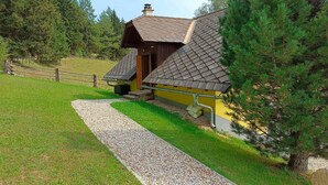 A rustic cabin with a sloped roof, surrounded by a gravel path and a wooden fence. - Alpine House in Prebl near Klippitztörl Ski Area (Prebl)