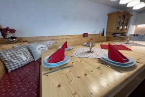 Un coin repas avec une table en bois dressée pour deux personnes, agrémentée de serviettes rouges et d’un verre.