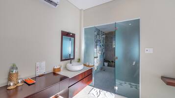 A modern bathroom with a wooden vanity, a white sink, a mirror, and a glass shower enclosure.