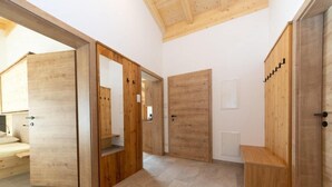 A modern interior with wooden doors, a bench, and a small table. - High-quality apartment with ski storage (Kleinarl)