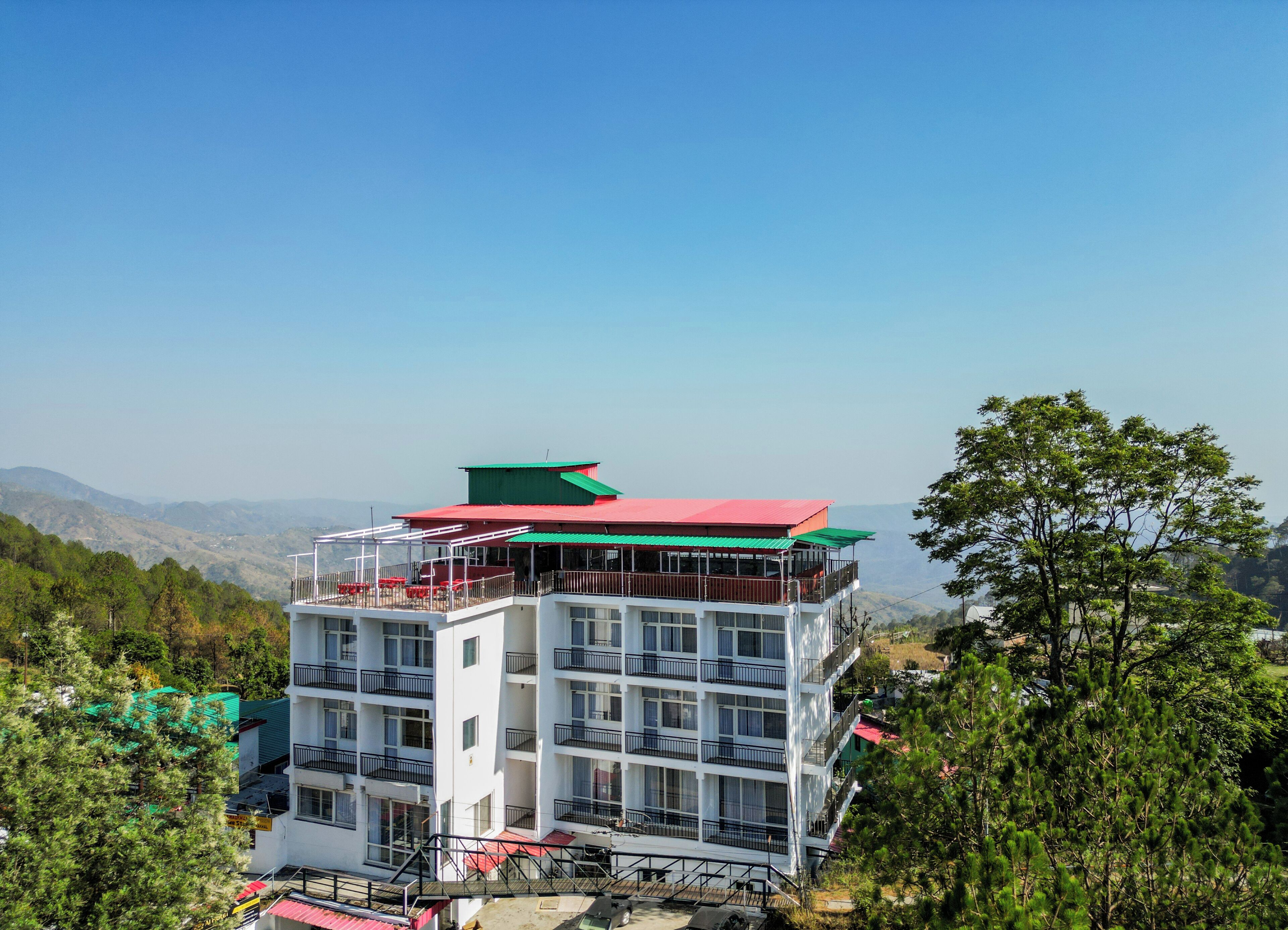 Ein mehrgeschossiges Hotel mit Balkonen, rotem Dach und Blick auf die umliegenden Berge.