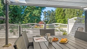 An outdoor patio with wicker furniture, a table with a magazine, a basket of croissants, and a white fence. - "Janna" - 200m from the sea by Interhome (Vordingborg)