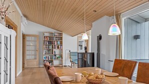 A dining area with a wooden table, chairs, and a bookshelf in the background. - "Janna" - 200m from the sea by Interhome (Vordingborg)