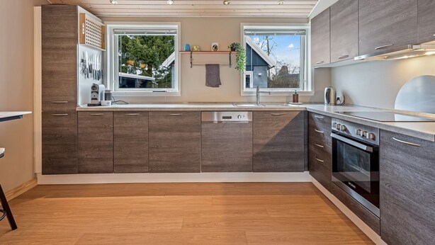A modern kitchen with wooden cabinets, a built-in oven, and a large window. - "Janna" - 200m from the sea by Interhome (Vordingborg)