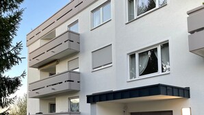 A multi-story building with balconies, a gated entrance, and a small garden area.