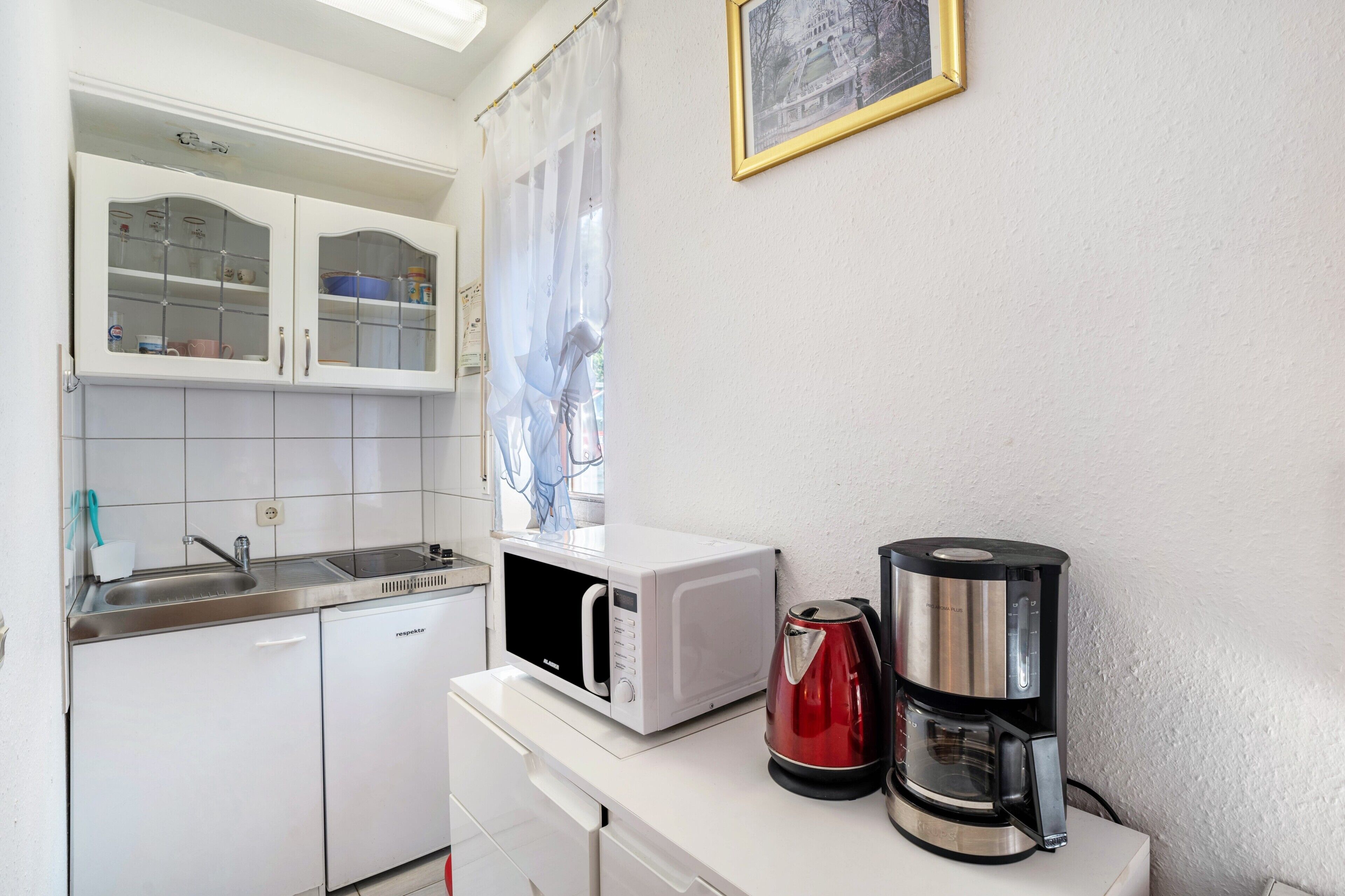 A compact kitchenette with a microwave, coffee maker, and a small refrigerator.