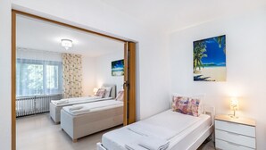 Un dormitorio con dos camas, una mesita de noche, un cuadro de playa y un radiador.
