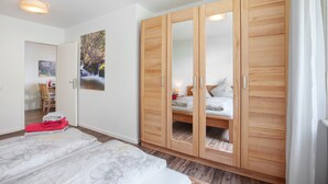 Quarto com guarda-roupa de madeira, cama com colcha floral e um quadro na parede.