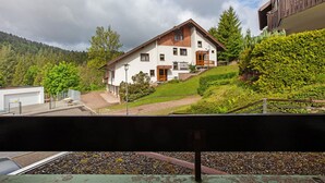 Uma casa de dois andares com telhado inclinado, varanda da frente e uma pequena sacada.