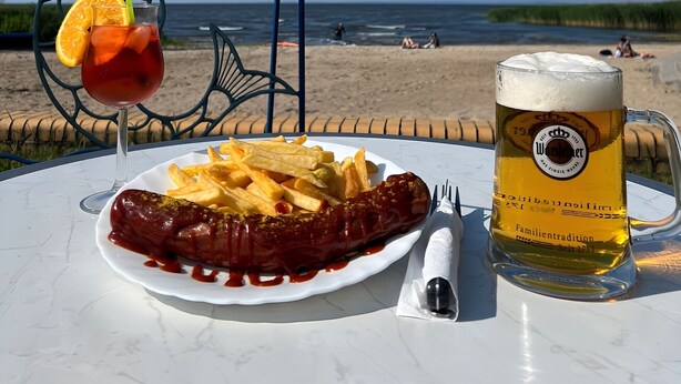 Una mesa con un plato de comida, una jarra de cerveza y una bebida con una rodaja de naranja.