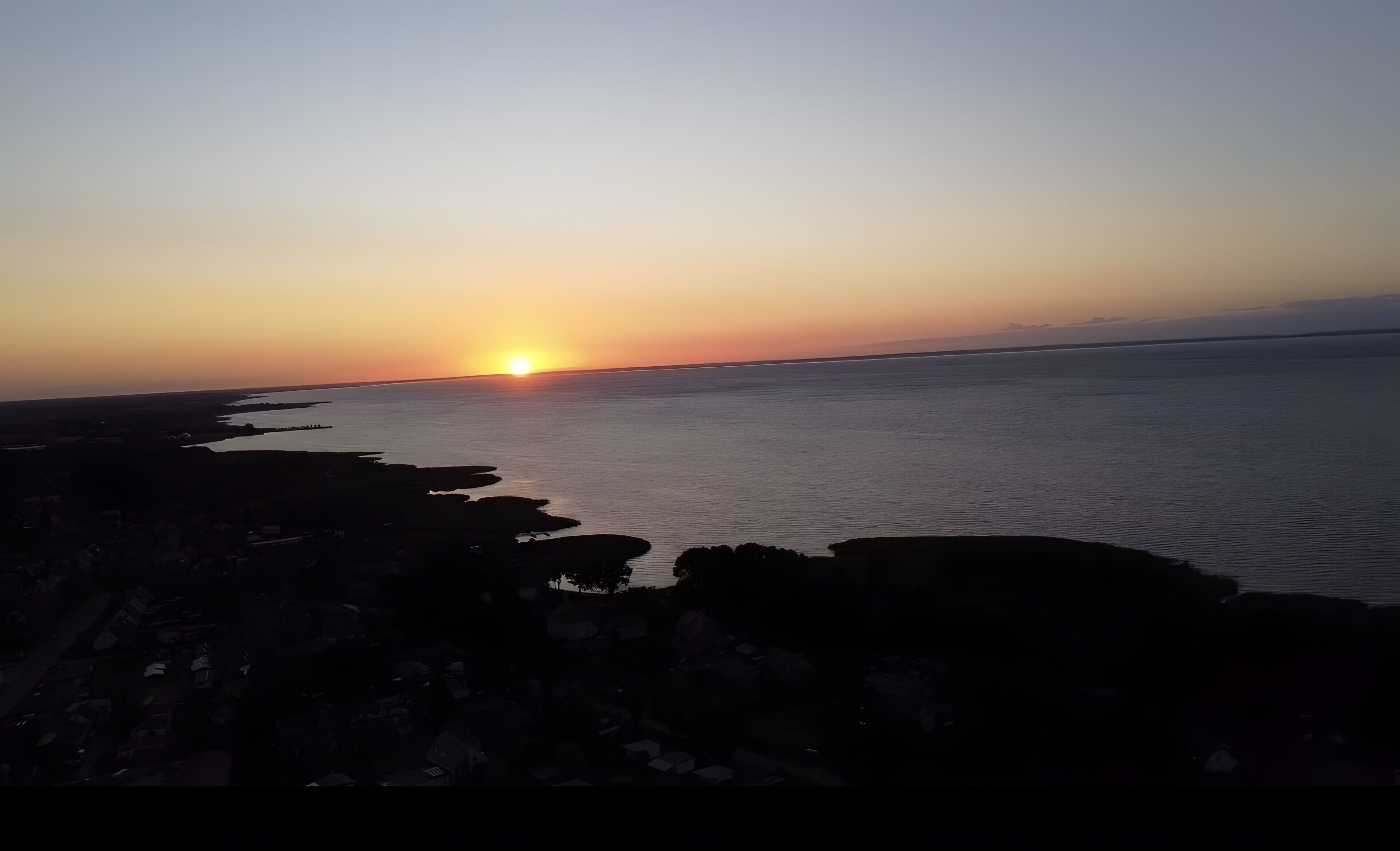 En vacker solnedgång vid kusten, med en stenig strand och ett lugnt hav.