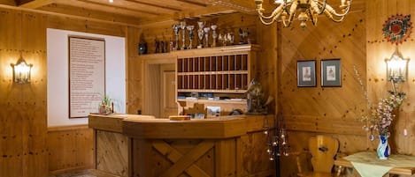 Un interior de madera con un mostrador de recepción, una araña, cuadros enmarcados y trofeos en estantes.