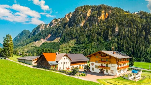 A traditional alpine-style building with a prominent wooden facade, situated in a lush green valley with a mountain backdrop. - Apartment in Radstadt near Ski Amadé (Radstadt)