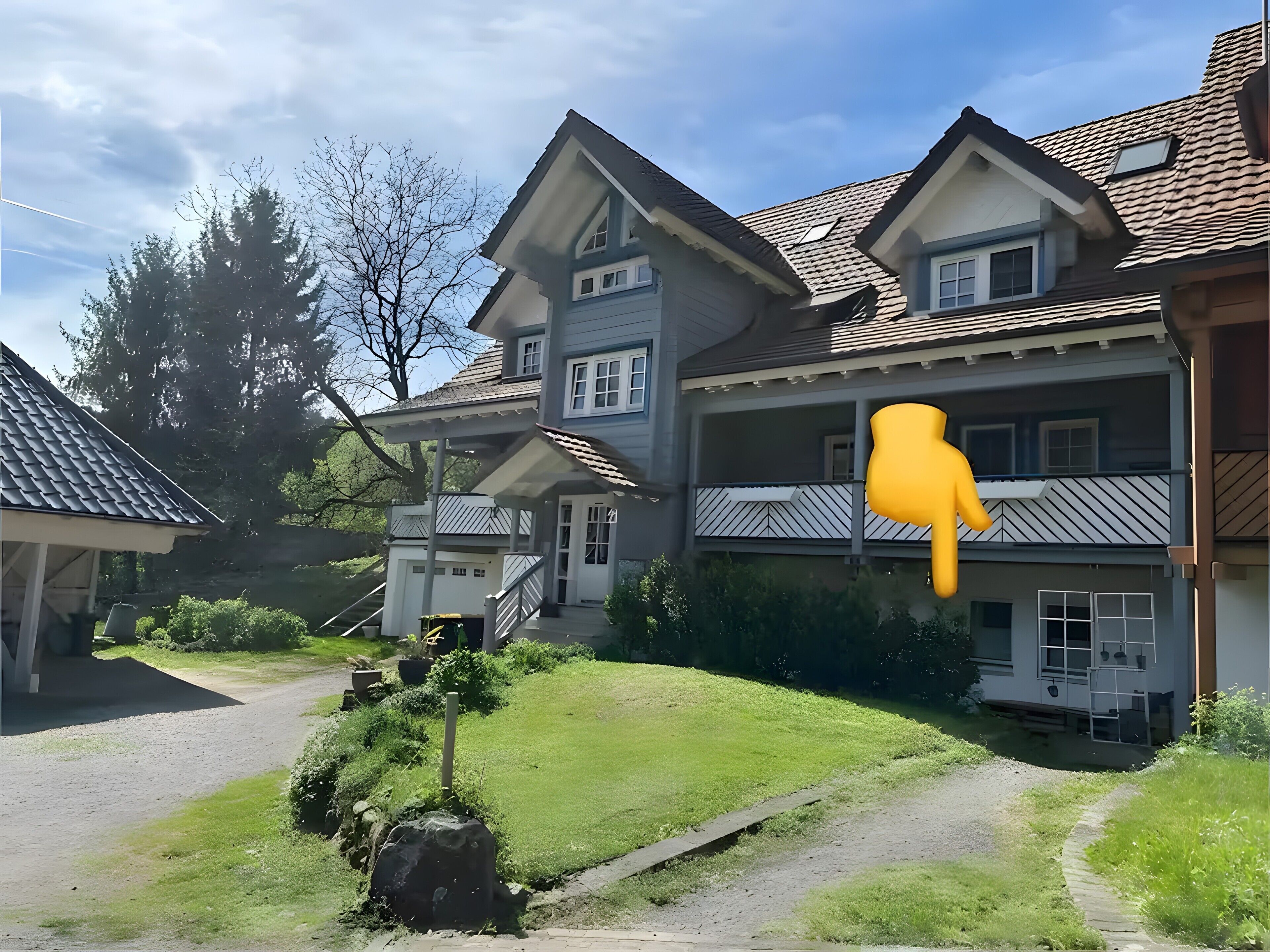 Ein zweigeschossiges Haus mit einer Veranda, einer sichtbaren Treppe und einem Weg zum Eingang.
