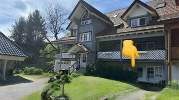 Ein zweigeschossiges Haus mit einer Veranda, einer sichtbaren Treppe und einem Weg zum Eingang.