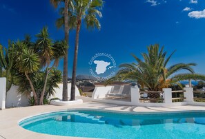A pool area with palm trees, a white wall, and a clear blue sky. - CostaBlancaDreams - Casa Fuente Salvaje in Moraira (Moraira)