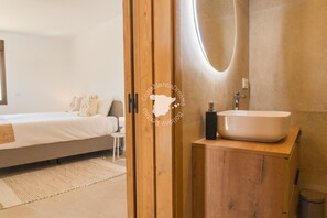 A modern bedroom with a large bed, a wooden wardrobe with a mirror, and a bathroom with a sink and a large mirror. - CostaBlancaDreams - Casa Fuente Salvaje in Moraira (Moraira)
