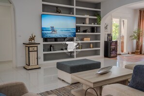 Ein modernes Wohnzimmer mit einem Flachbildfernseher, einem Holzschrank und einer grauen Bank.