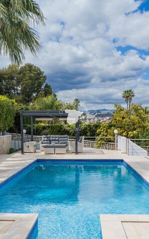 A swimming pool with a pergola and seating area, surrounded by lush greenery and a view of a cityscape. - CostaBlancaDreams - Casa Monica in Calpe (Calpe)