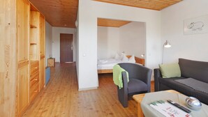 Habitació amb sòl de fusta, un llit, un sofà, una cadira i un armari.