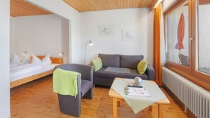 Habitació amb llit, sofà, taula i finestra amb cortines.