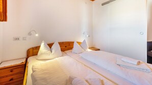 A bedroom with a wooden headboard, white bedding, a bedside table, and a wall-mounted light fixture. - Haus Kehrwieder Apartment 3: Balcony, Mountain View, Hochschwarzwald Card, Wi-Fi, Parking (Todtnau)