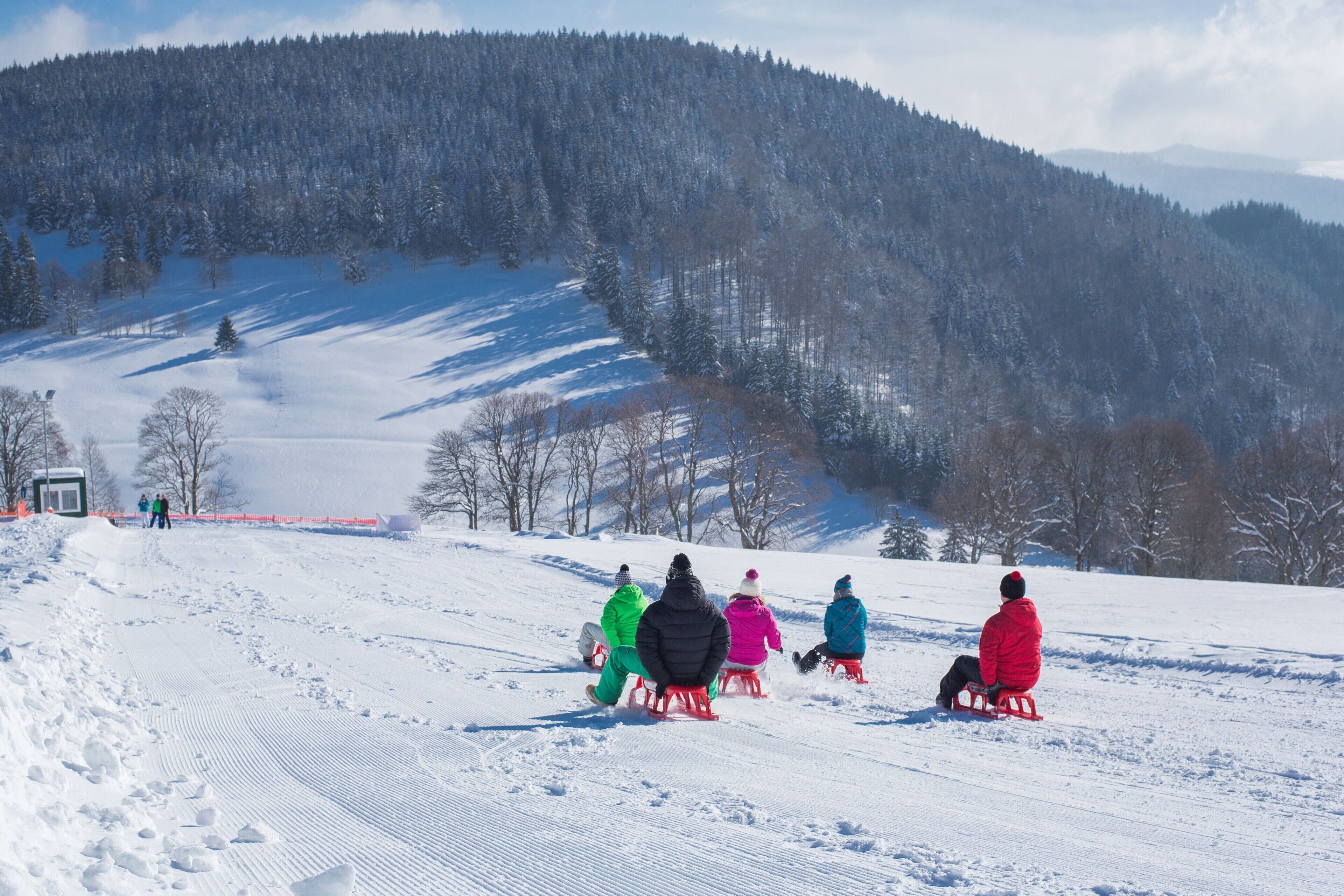 A snowy landscape with people sledding.