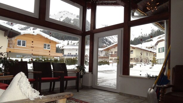 A cozy room with large windows, wooden furniture, and a view of snowy mountains. - Holiday Home in Holzgau near Snowworld Ski Area (Holzgau)