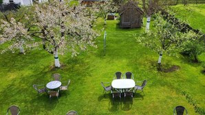A garden with four round tables and chairs, surrounded by blooming trees. - Holiday Home in Holzgau near Snowworld Ski Area (Holzgau)