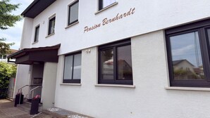 Ein Gebäude mit der Aufschrift 'Pension Bernhardt' an der Fassade, das einen modernen Baustil mit großen Fenstern und einem Flachdach aufweist.