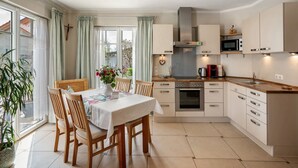 Une cuisine moderne avec un coin repas, comprenant une grande fenêtre, une croix au mur et un four à micro-ondes.