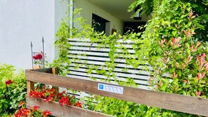 En träbänk med en parkeringsskylt, omgiven av frodig grönska och blommande växter.