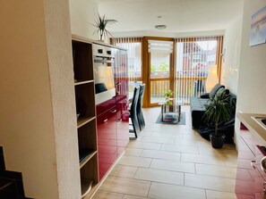 Una sala de estar moderna con un sofá rojo, una mesa de centro de vidrio y vistas al balcón exterior.