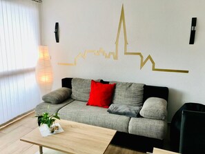 Una sala de estar moderna con un sofá, una mesa de centro, una lámpara de pared y un elemento decorativo en la pared.